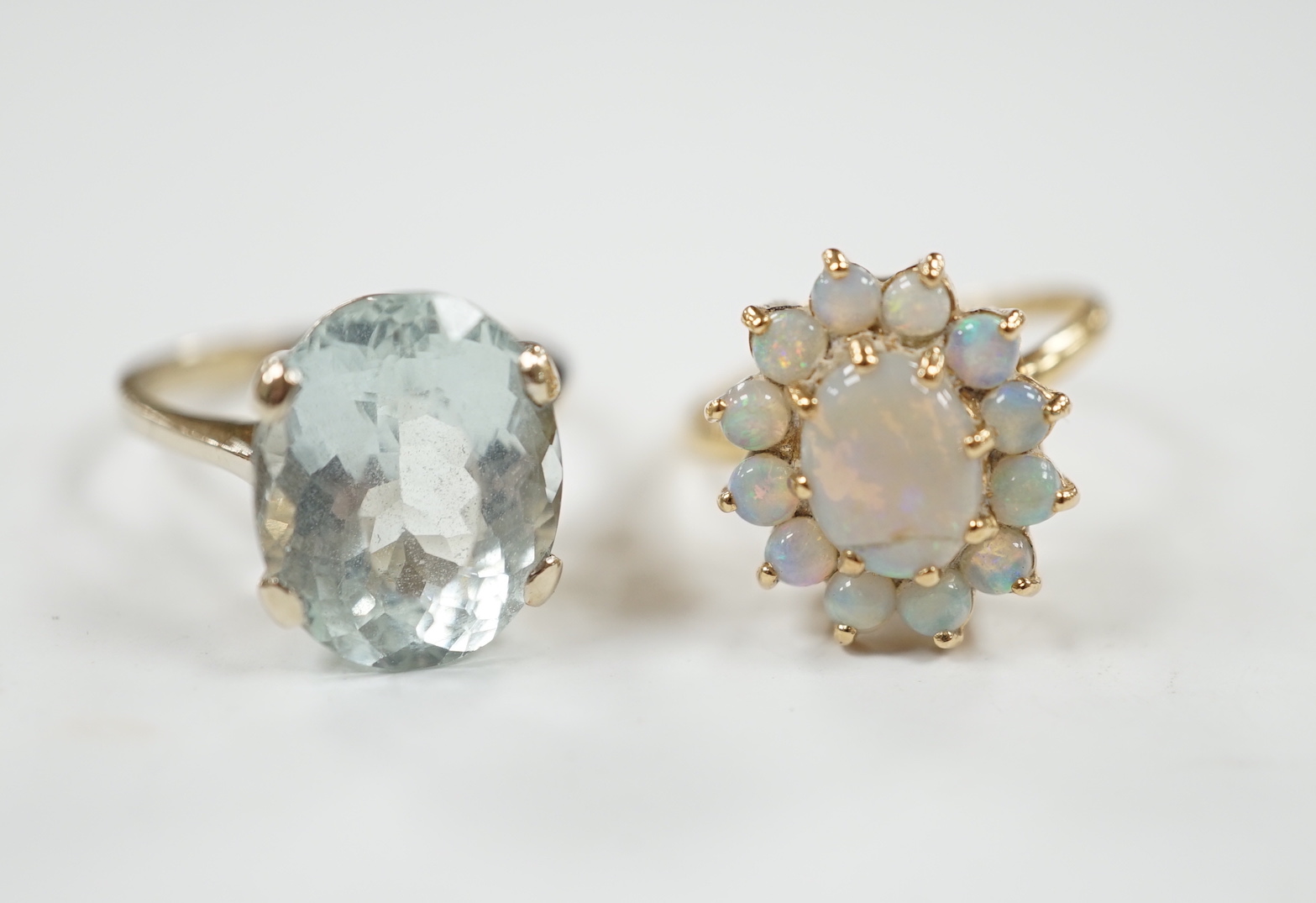 A 14k yellow metal and white opal set oval cluster ring, size P/Q, gross weight 4.1 grams and a gilt white metal? and oval fancy cut aquamarine set ring.